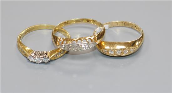 Two early 20th century 18ct gold and five stone diamond rings and a later 18ct gold and three stone diamond ring.